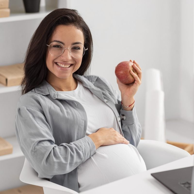 smiley-pregnant-woman-home-holding-apple